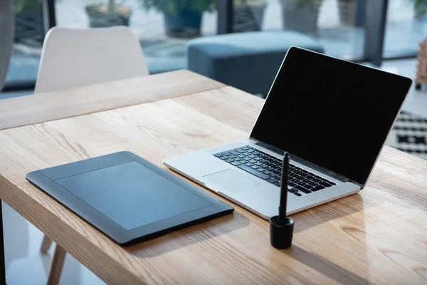 Laptop com tablet gráfico em mesa no escritório — Fotografia de Stock