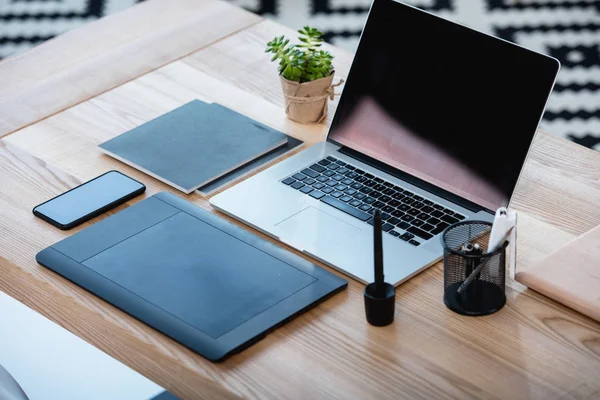 Ноутбук з графічним планшетом і смартфон на столі — стокове фото