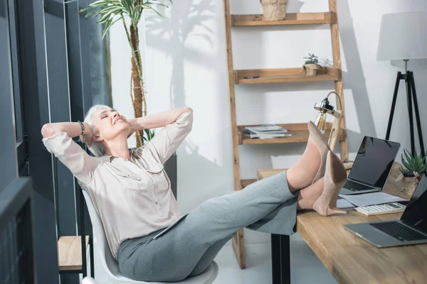 Geschäftsfrau mit Beinen auf dem Tisch — Stockfoto