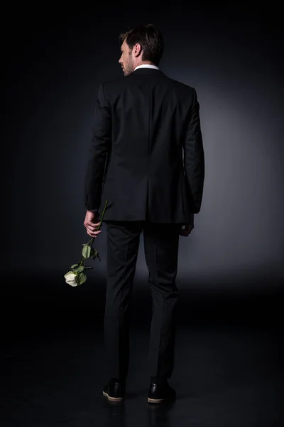 Людина в офіційному носінні тримає троянду — стокове фото