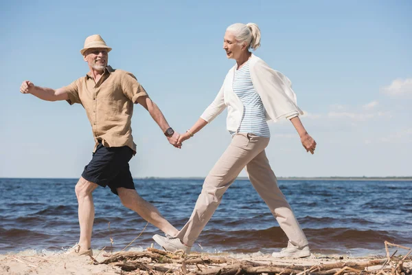 Pareja de ancianos caminando en la playa - foto de stock