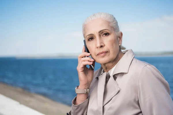 Старшая женщина разговаривает по смартфону на набережной — стоковое фото
