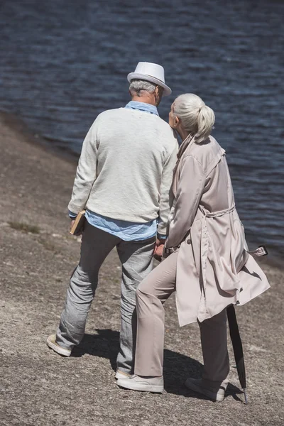 Pareja de ancianos caminando en la orilla del río - foto de stock