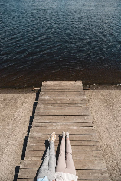 Пара, лежащая на деревянном тротуаре у реки — стоковое фото