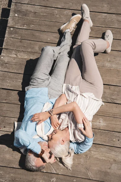 Pareja de ancianos acostados en el pavimento de madera - foto de stock