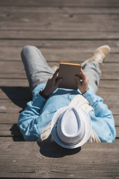 Mann liegt auf Gehweg und hält Buch in der Hand — Stockfoto