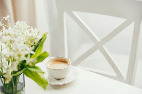 Xícara de café com buquê de flores na mesa — Fotografia de Stock