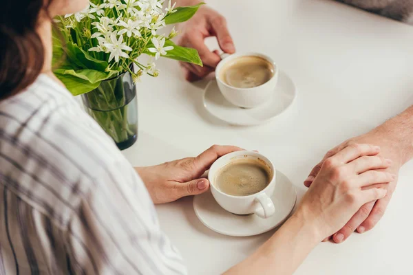 Couple drinking coffee and holding hands — Stock Photo