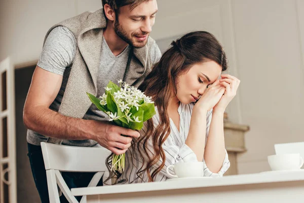 Homem apresentando flores para namorada em casa — Fotografia de Stock