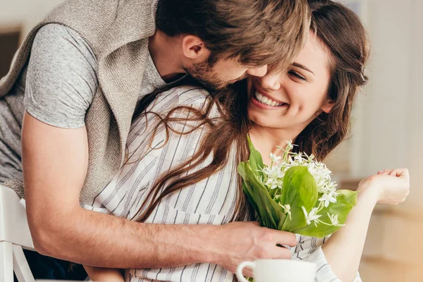 Young couple embracing with bouquet of flowers — Stock Photo