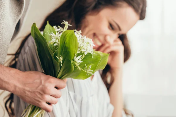 Homme présentant des fleurs à petite amie à la maison — Photo de stock