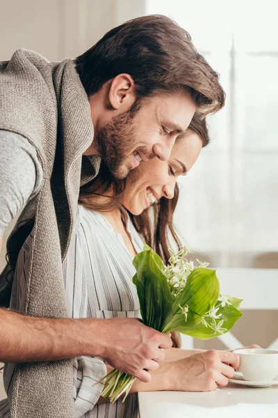 Man embracing girlfriend with bouquet of flowers — Stock Photo