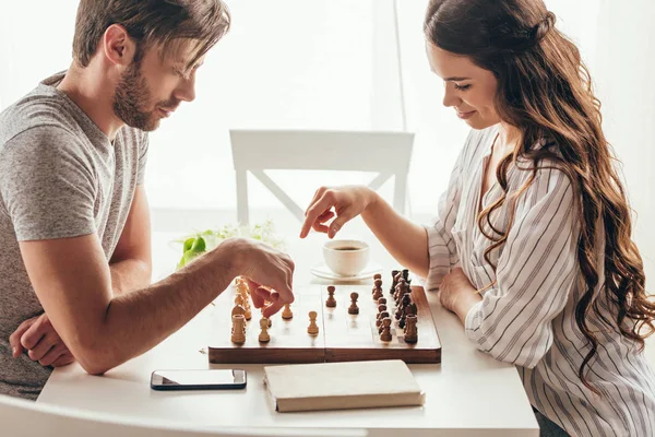 Pareja joven jugando ajedrez en casa - foto de stock