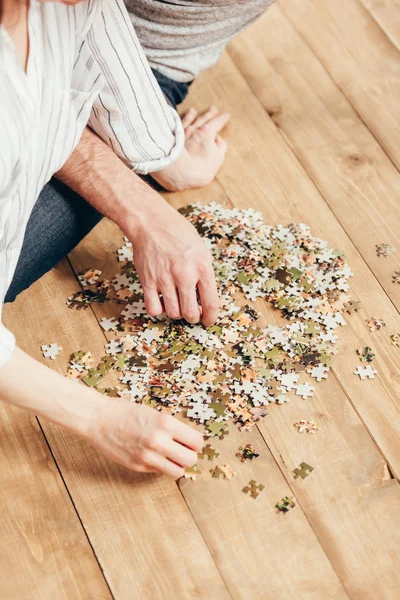 Couple collecting puzzle on wooden floor — Stock Photo