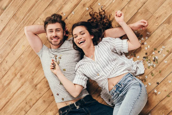 Giovane coppia sorridente sdraiata sul pavimento — Foto stock