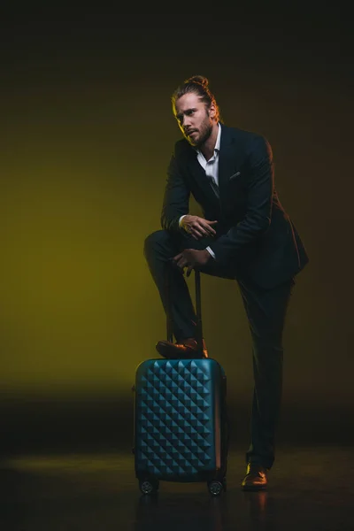 Pensive man in suit leaning on suitcase — Stock Photo