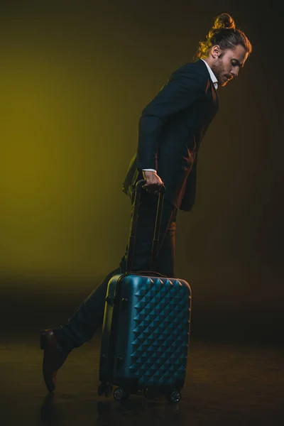 Young man in suit walking with suitcase — Stock Photo