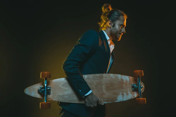 Людина в смокінгу біжить і тримає скейтборд — стокове фото
