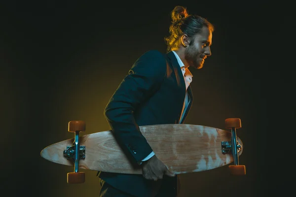 Uomo in smoking correre e tenere skateboard — Foto stock