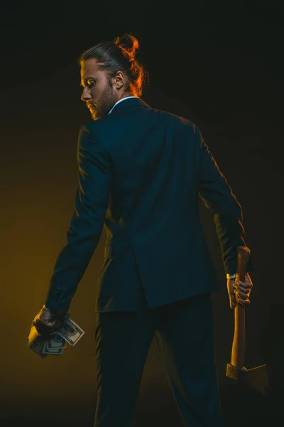 Young man with ax and dollar banknotes — Stock Photo