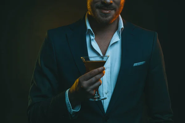 Человек в смокинге держит стакан с коктейлем — стоковое фото