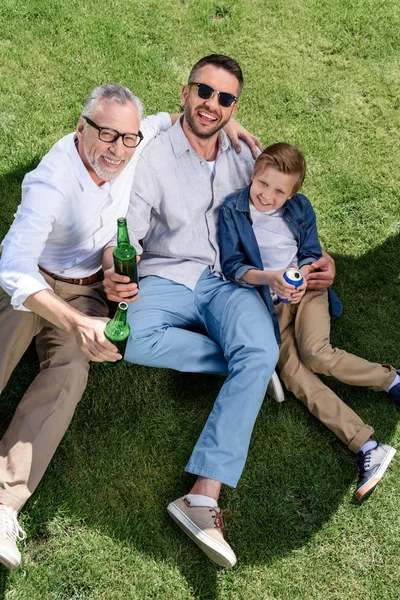 Abuelo, padre e hijo abrazándose en la hierba - foto de stock