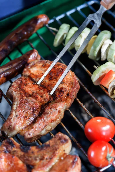 Meat pricked by carving fork on grill — Stock Photo