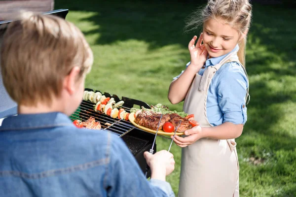 Kids preparing meat and vegetables on grill — Stock Photo