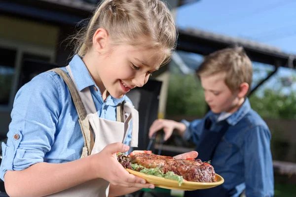 Kid girl holding plate with steaks — Stock Photo