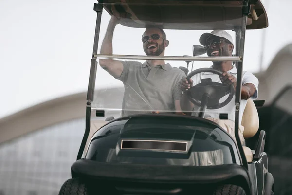 Amigos dirigindo carrinho de golfe — Fotografia de Stock