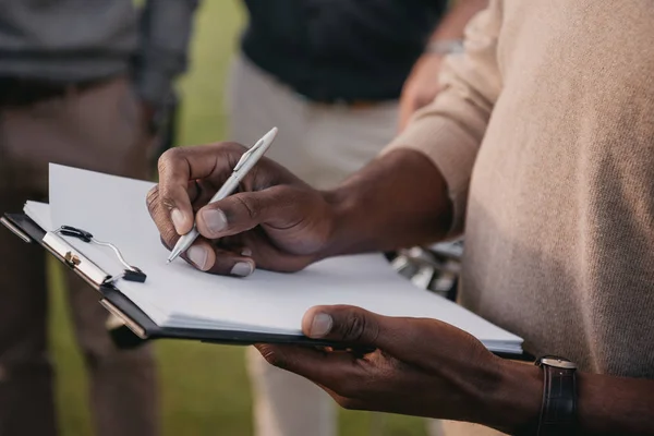 Man writing on paper in clipboard — Stock Photo