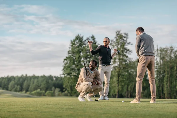 Amigos multiétnicos jugando al golf - foto de stock