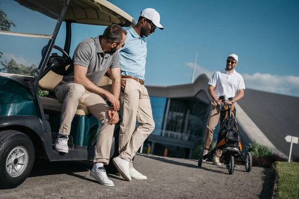 Hombres de pie cerca del carrito de golf - foto de stock