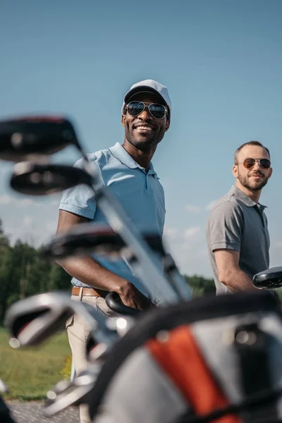 Deportistas sonrientes que van al campo de golf - foto de stock