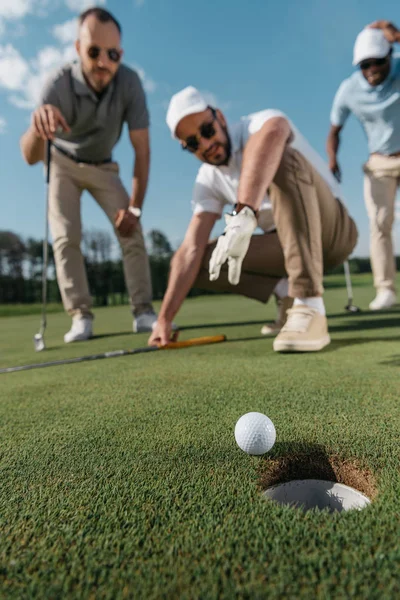 Giocatori di golf guardando palla vicino buco — Foto stock