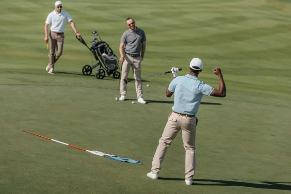 Golfista celebrando el éxito con amigos pitch - foto de stock