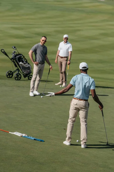 Golfistas multiétnicos hablando durante el juego - foto de stock