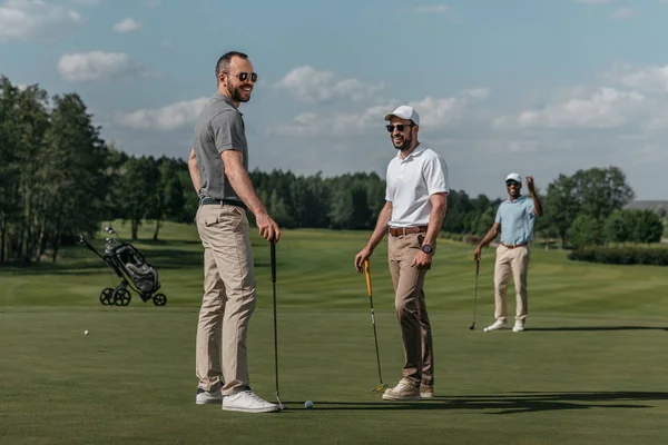 Amigos sonrientes jugando al golf - foto de stock