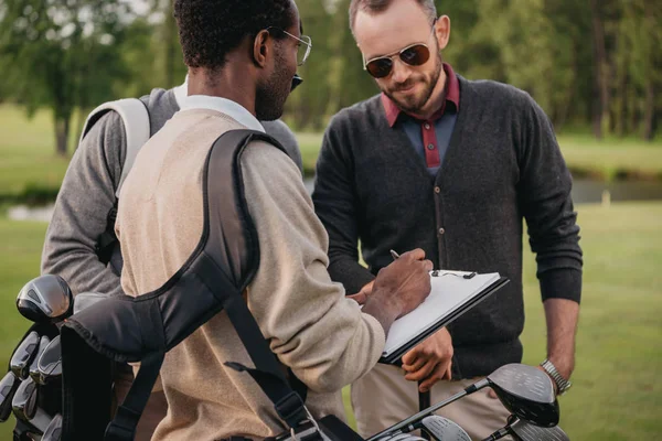 Man writing on paper in clipboard — Stock Photo