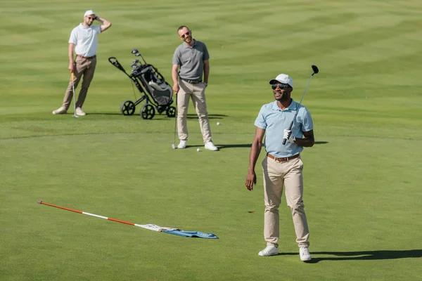 Спортсмены, стоящие с клюшками для гольфа на поле — стоковое фото
