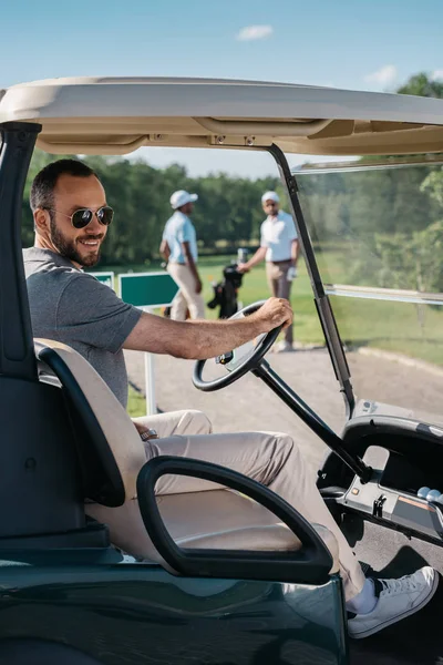 Junger Mann sitzt am Golfwagen — Stockfoto