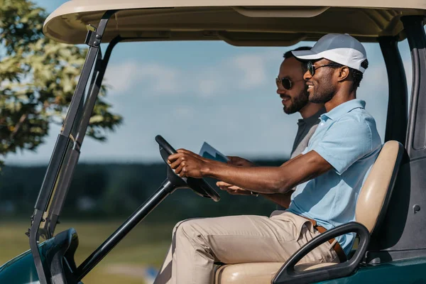 Друзі говорять під час їзди на візку для гольфу — стокове фото