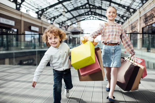 Niños felices sosteniendo bolsas de compras - foto de stock