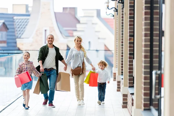 Family with shopping bags holding hands — Stock Photo