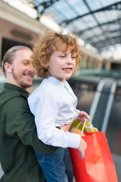 Vater hält Sohn mit Einkaufstüten — Stockfoto