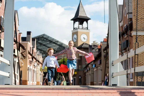 Niños felices sosteniendo bolsas de compras - foto de stock