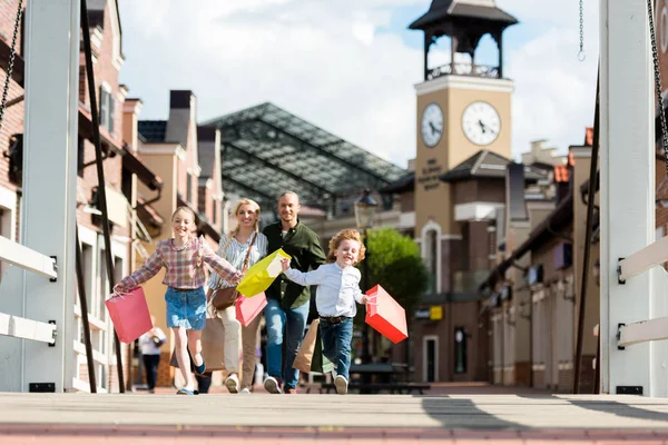 Familia corriendo con bolsas de compras en la calle - foto de stock