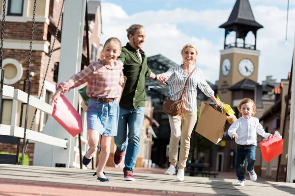 Family running with shopping bags on street — Stock Photo