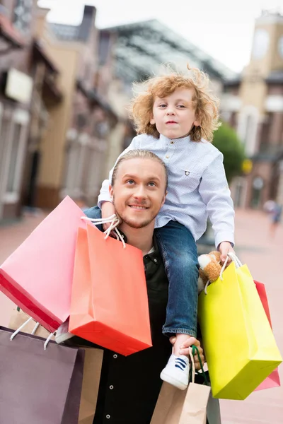 Padre e hijo con bolsas de compras en la calle - foto de stock