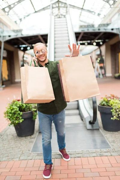Homme marche avec des sacs à provisions dans le centre commercial — Photo de stock